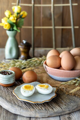 A rustic country scene of eggs in a basket with one boiled egg sliced in front.