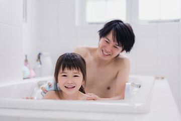 小さな娘と一緒にお風呂に入るお父さん