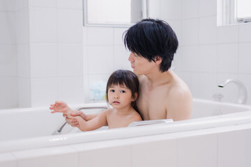 小さな娘と一緒にお風呂に入るお父さん