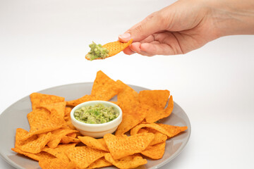Woman hand with nachos chips and guacamole dip on white background