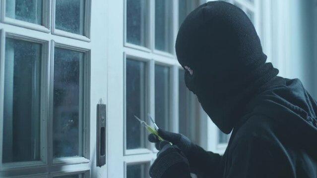 Close Up Of Thief Man Holding Flashlight Looking Inside The House Before Trying To Open The Door 
