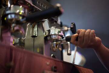 Coffee Machine. The barista's hand is attaching the portafilter to the coffee machine group head.