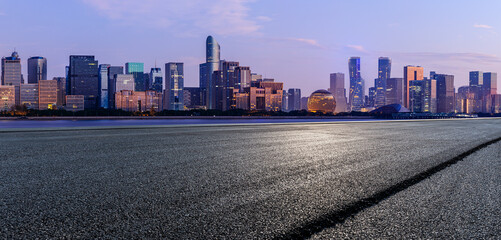 Asphalt road and city skyline with modern commercial buildings in Hangzhou at sunrise, China.