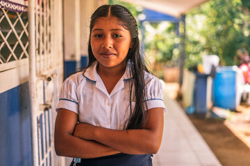 Nicaraguan elementary student girl smiling and looking at the camera with her arms crossed in a...
