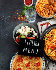 Italian food assortment on dark background.