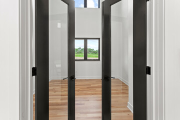 large empty room with black windows and natural finished hardwood flooring