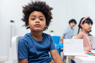 Portrait of Stressed African black child boy sitting in classroom. 