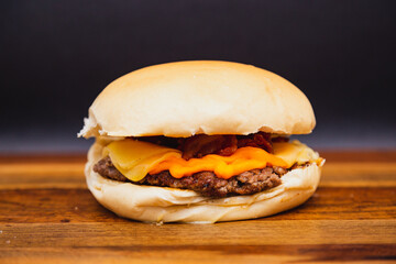 Delicious traditional Brazilian burger, X burger cheader, meat and cheese cheader. on wooden board.