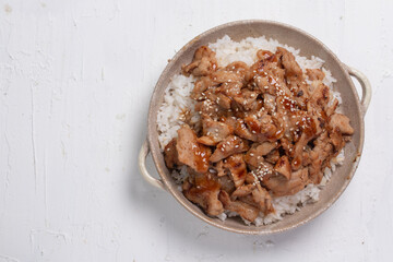 Roast pork with teriyaki sauce sprinkled with white sesame seeds on a white background.