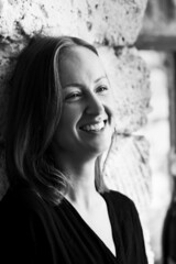 Black and white photograph of an attractive smiling woman. A large portrait on a stone background. Vertical photo.