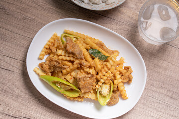 Stir-fried pork with red curry paste and young coconut shoots in a white plate