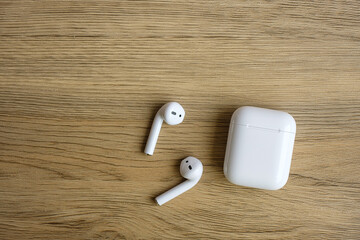 White wireless earphone or headphones on table for using with smartphone. Technology concept