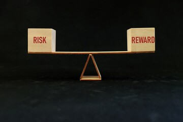 Balancing risk and reward word on seesaw scale in dark black background. Risk-reward ratio business...