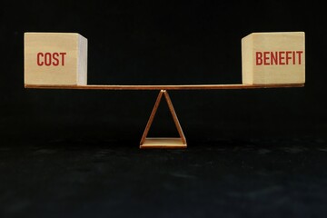 Balancing cost and benefit word on seesaw scale in dark black background. Cost-benefit ratio...