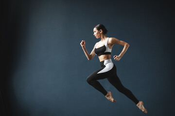 Obraz na płótnie Canvas Beautiful athletic woman in a jump posing