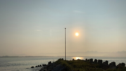Early morning sea view with sunrise and the pole at the end of the pier
