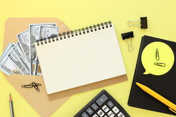 Notepad on office desk with calculator and sticker, stationery and office supplies. Blank notepad for typing copy or text on an envelope with money. flat lay yellow color background.
