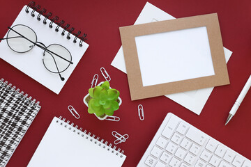 top view image of an open notebook with blank pages next to a potted plant on a red background. ready to add text or layout.