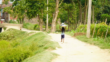 Fototapeta premium An unidentified village little girl is carrying home utensils after washing .