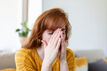 Sad woman feels miserable desperate sit on sofa look out the window thinking about personal...