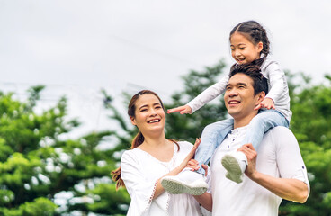 Portrait of enjoy happy love asian family father and mother holding hug cute little asian girl child smiling play and having fun moments good time in summer park at home