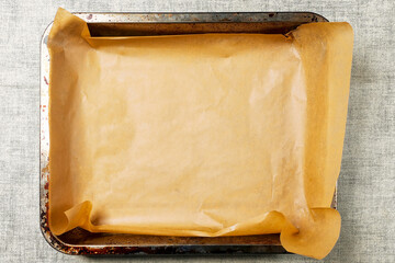 Old used baking tray with brown paper. Cooking food in the oven. Preparation for baking meat, fish and bakery products. Simple table cloth background. Top down view - Powered by Adobe