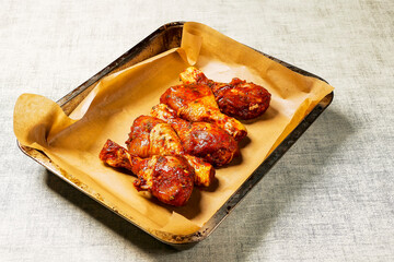 Asian style marinated chicken drumsticks on a brown baking paper and old baking tray ready to be cooked. Poultry product, summer range for barbeque. Red color marinate. Meat industry.