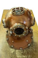 Old brass diving helmet for work deep underwater with side windows on a wooden table surface. History and hard dangerous work concept.