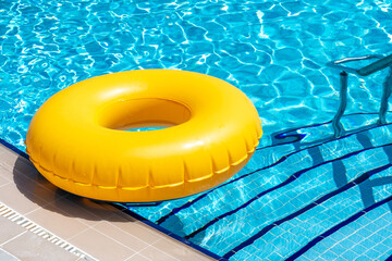 Yellow ring floating in blue swimming pool. Inflatable ring, rest concept
