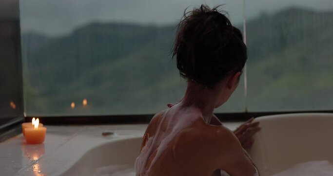 Attractive woman in jacuzzi tub with candles lit from behind