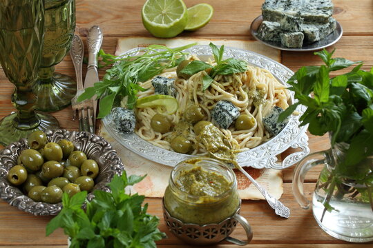 Pesto sauce with spaghetti and blue cheese on a wooden table	
