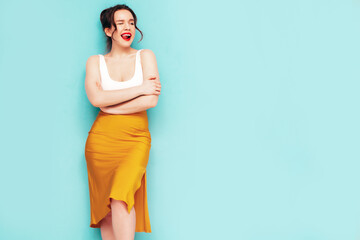 Obraz premium Young beautiful smiling female in trendy summer yellow skirt clothes. Sexy carefree woman posing near wall in studio. Positive model having fun. Cheerful and happy. Isolated