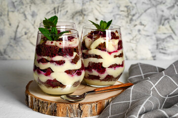 Two transparent glass with layered dessert, chocolate cake and whipped cream, berries 