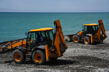 Two excavators with a wheel loader levels the sea coast.