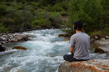 Young man preforms yoga in mountains river
