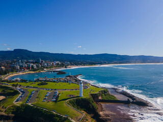 Fototapeta na wymiar Low aerial drone view of Flagstaff Point Lighthouse at Wollongong on the New South Wales South Coast, Australia looking toward Wollongong North Beach on a sunny day 