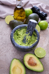 making guacamole - crushed avocado in marble mortar on grey concrete table