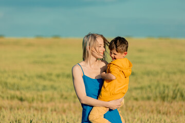 Mother with son in ukrainian national colors in wheat fie