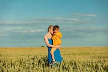 Mother with son in ukrainian national colors in wheat fie