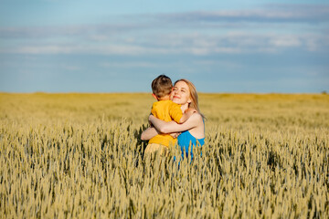 Mother with son in ukrainian national colors in wheat fie