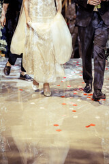 Low section of bride and groom walking on rose petals