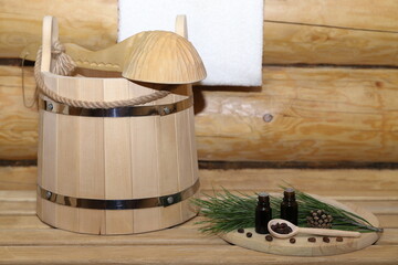 Two bottles of healing essential oil are on wooden cover next to nuts, cone and green cedar branch...