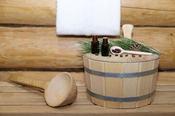 Two bottles of healing essential oil are on wooden cover next to nuts, cone and green cedar branch...