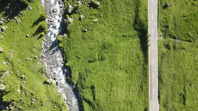 Cycling in Switzerland a view from above. Three bicycle driver passing buy a river in nature.
