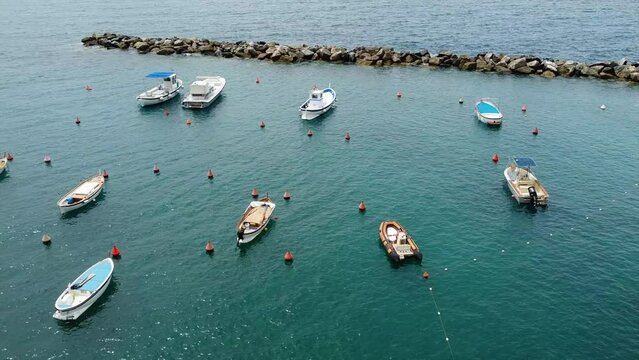 Europe, Italy , Liguria, Levanto  - Drone aerial of small harbor with boats moored in the sea near the coast beach and protected by brush of large stones in the sea - peace and tranquility in Liguria
