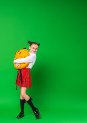 happy smiling schoolgirl in uniform with a backpack and a notebook in her hands poses on green background in the studio. The child is happy and goes to school with pleasure. Back to school. copy space