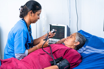 Nurse or doctor checking bp or blood pressure of senior sick patient at hospital on bed - concept...