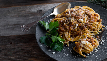 Spaghetthi Bolognese on a dark plate on wooden table