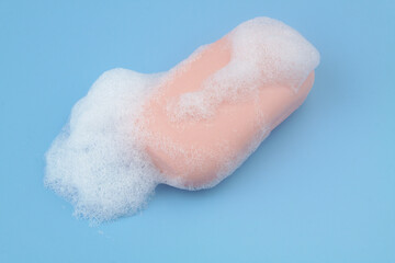 Pink soap with foam bubbles on blue background.