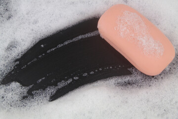 Fototapeta premium Pink soap bar and white soap foam on black background. 